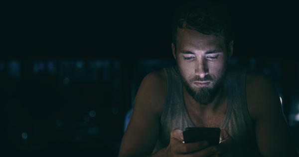 Man In Darkness Looking At Phone Worried